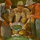A turn-of-the-century hand-tinted postcard image of three happy miners gazing at gold nuggets in a mining pan.